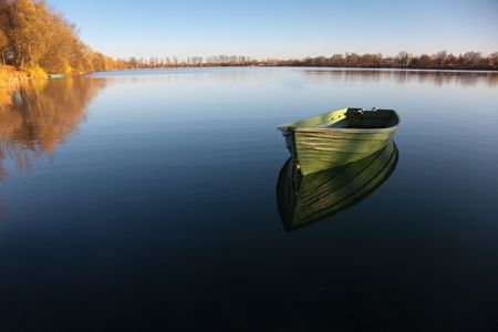 6006252 - single row boat on lake with reflection in the water