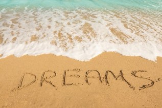 49150747 - dreams message on the beach sand - vacation and travel concept