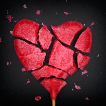 42161286 - broken red heart shaped lollipop. closeup. vignette.